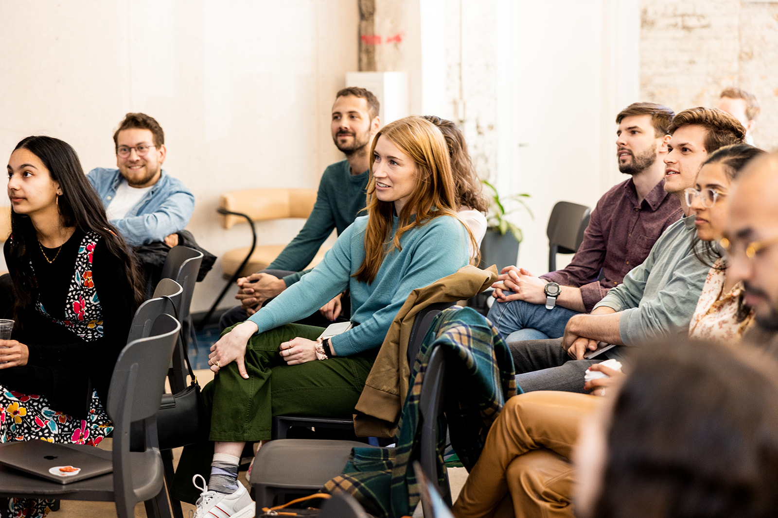 Ethena team members seated together at an all-hands, laughing and listening